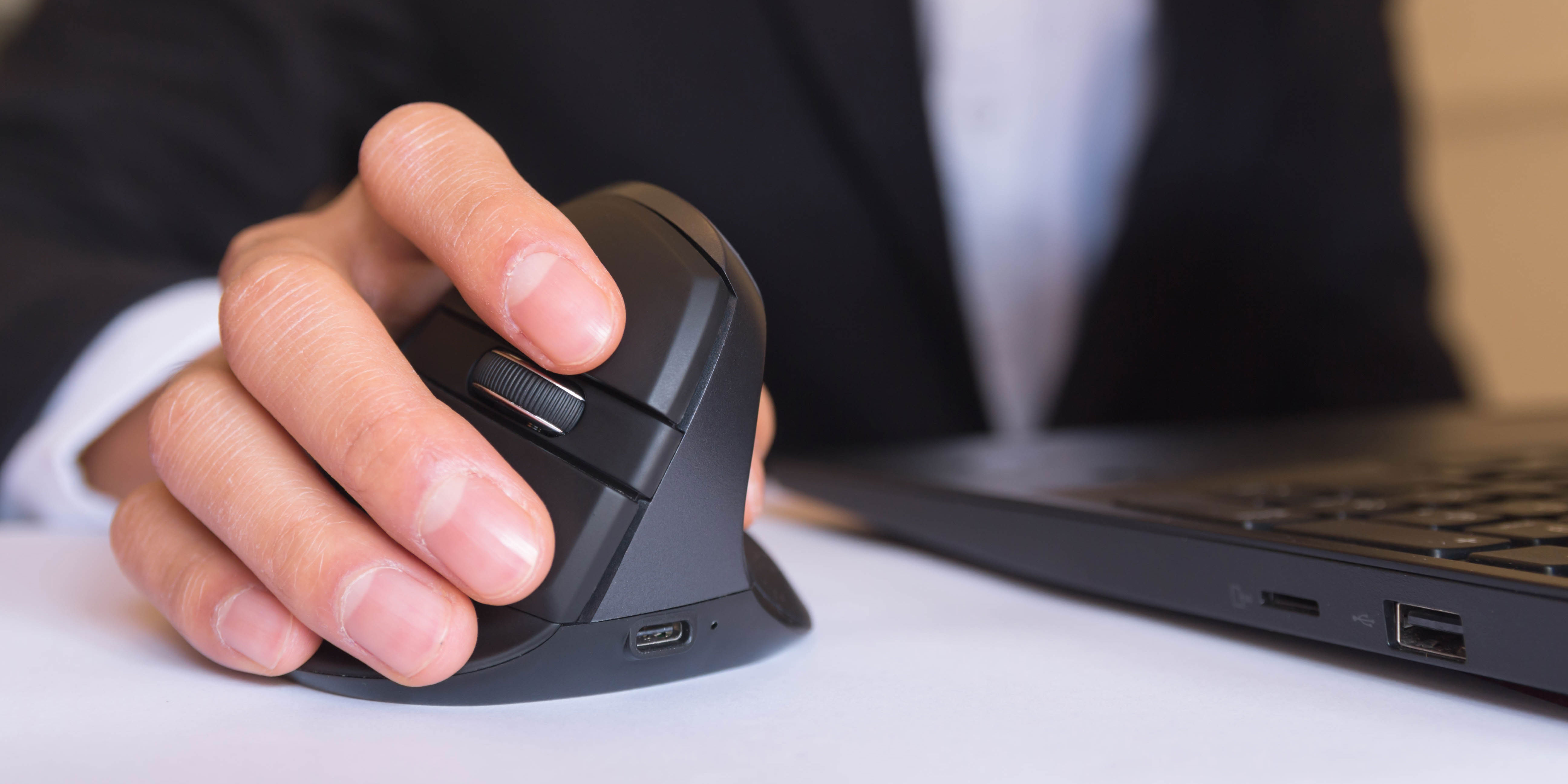 An ergonomic computer mouse being used on a desk